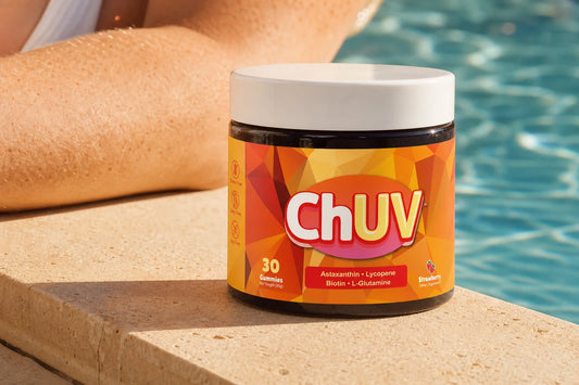 ChUV tanning gummies bottle on a poolside ledge beside freckled skin showing a natural warm glow, tanning gummies for redheads and freckled skin